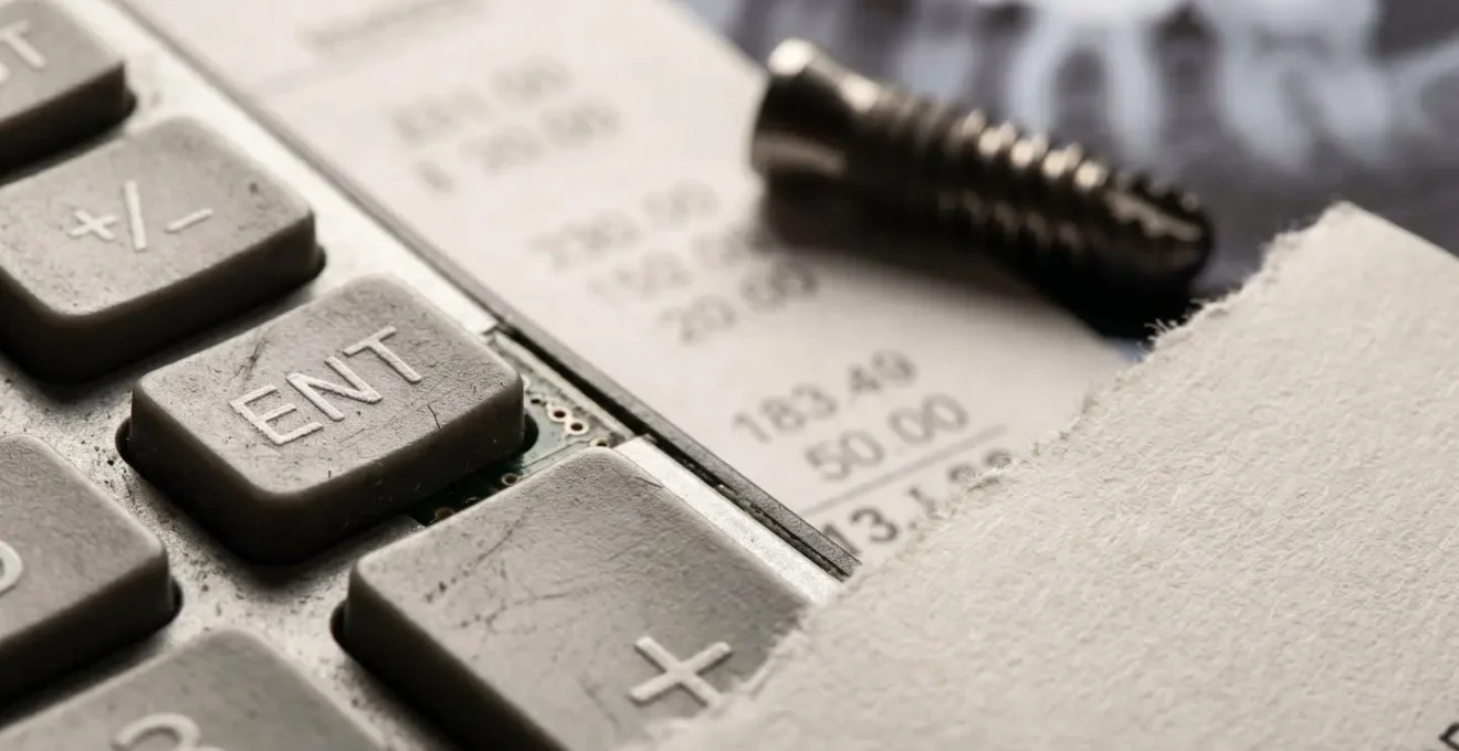 Calculatrice et documents dentaires montrant la répartition des coûts